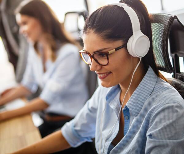 Friendly young woman helpline operator with headphones in call center Friendly young woman helpline operator with headphones in call center